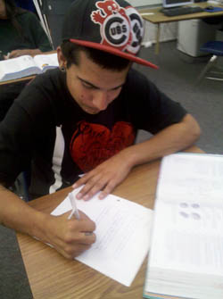 Student writing at desk.